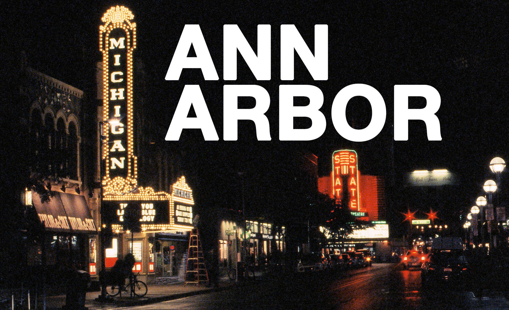 A night image of the Michigan Theater with the State Theater in the background shot on 35mm film with visible grain and "Ann Arbor" in white block letters.
